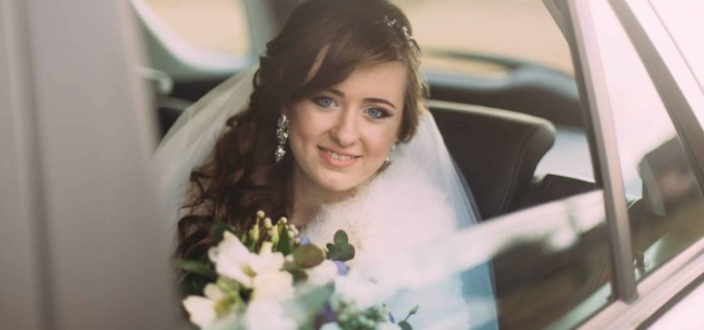 Bride in wedding car holding bouquet preparing for UK marriage visa application
